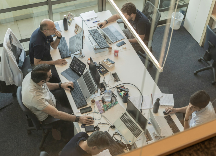 Four people working at desks in a modern office.